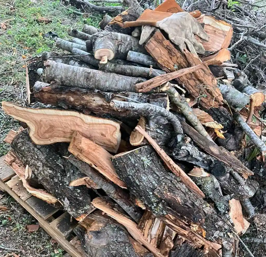 Pile of peach wood pieces for BBQ sitting on wooden pallet.
