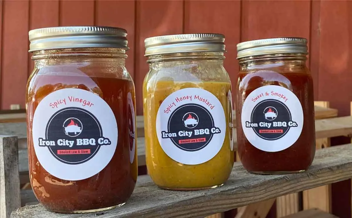 Three mason jars, each with a different sauce from Iron City BBQ.