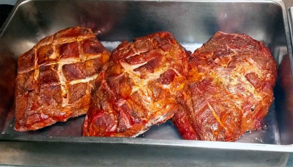 Smoked pork shoulders with crosshatched bark, ready for pulled-pork service.