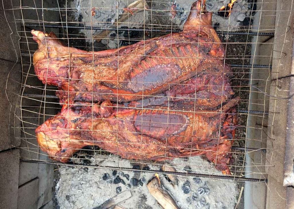 Whole hog, butterflied, on open cinder block pit over charcoal and hardwood embers.