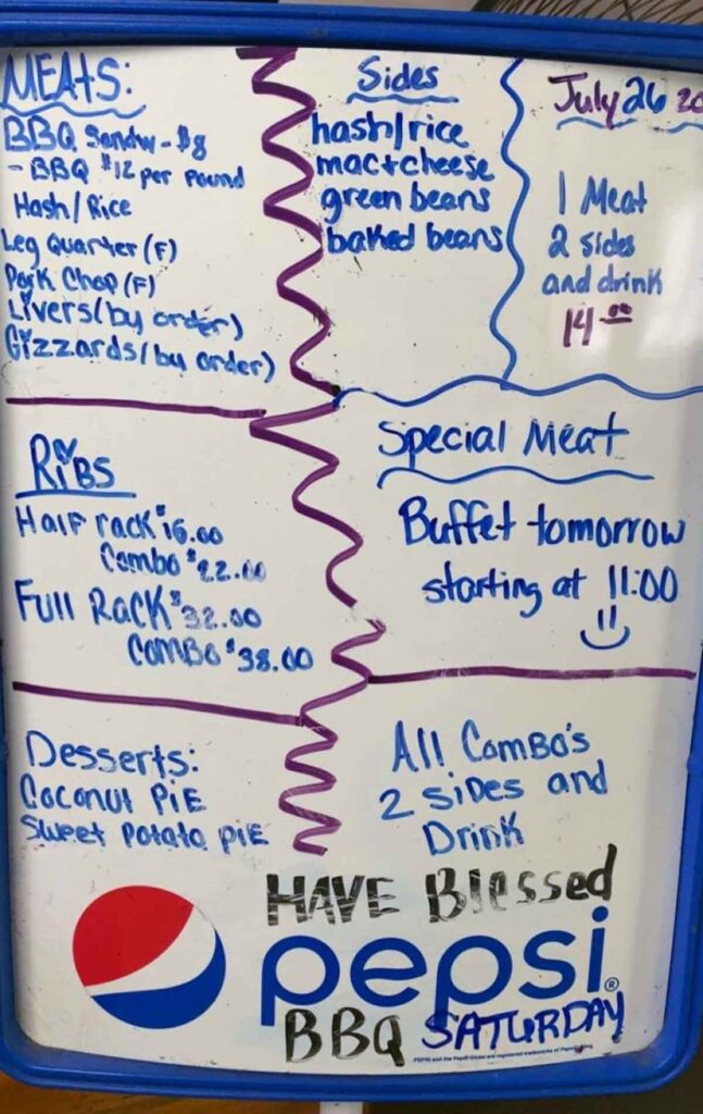 Handwritten menu board listing hash and rice, ribs, sides, and house desserts.