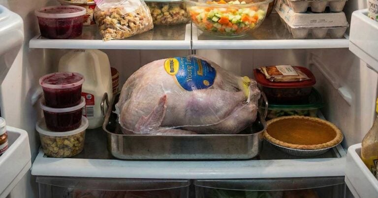 Frozen turkey thawing on a tray in a 40°F refrigerator.
