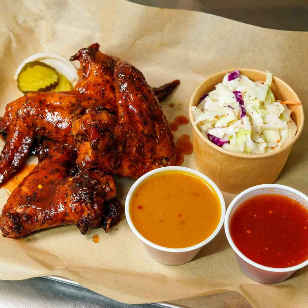 Sauced wings served with slaw, pickles, and two dipping sauces.