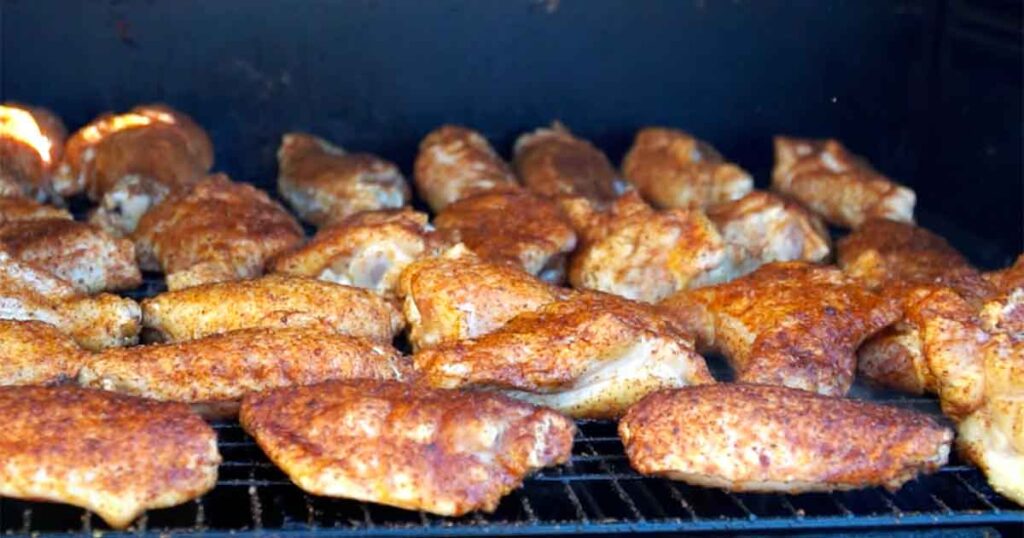 Chicken wings smoking on a rack in a Masterbuilt Gravity Series smoker.