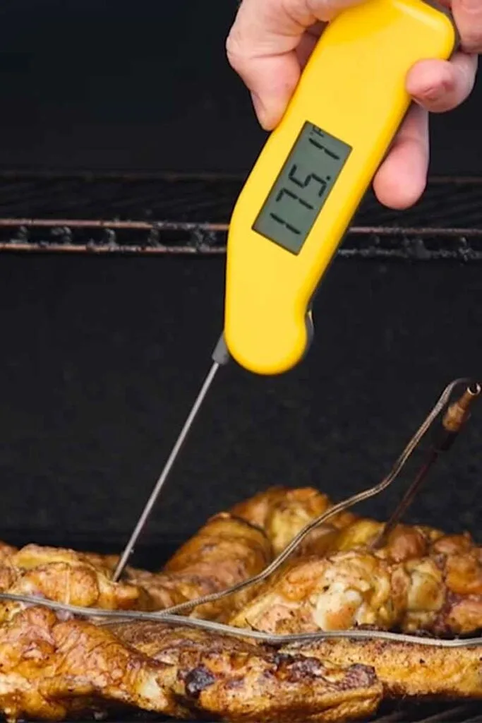 Instant-read thermometer reads 175°F in a chicken wing on the grill.