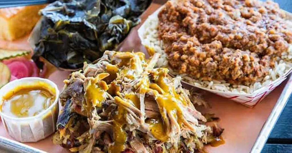 BBQ tray with pulled pork, hash, and sides next to the South Carolina BBQ Trail map.