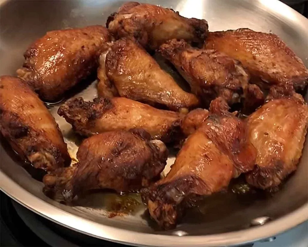 Wings crisping in a skillet in a single layer over medium heat for a quick reheat and browned skin.