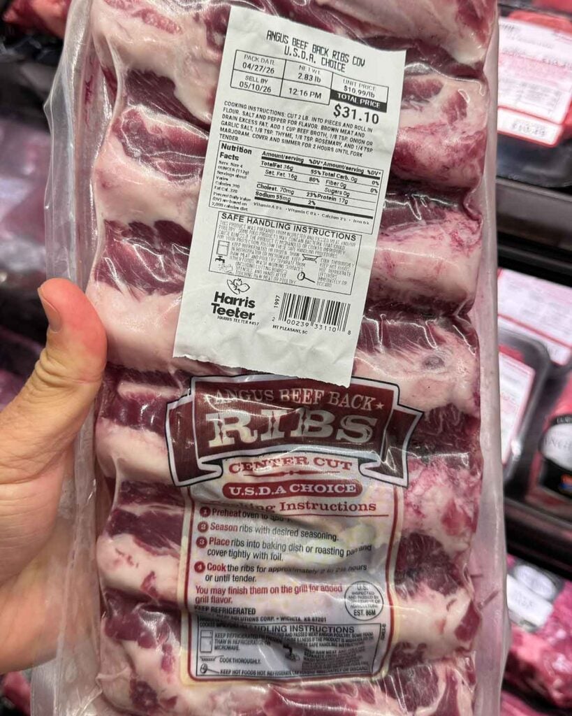Packaged Angus beef back ribs at a grocery store with the label and rack-style bones visible through the plastic.