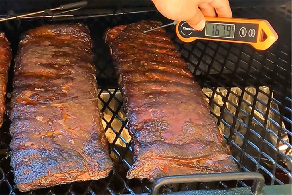 Thermometer checking reheated ribs on the grill, showing 167.9&deg;F.