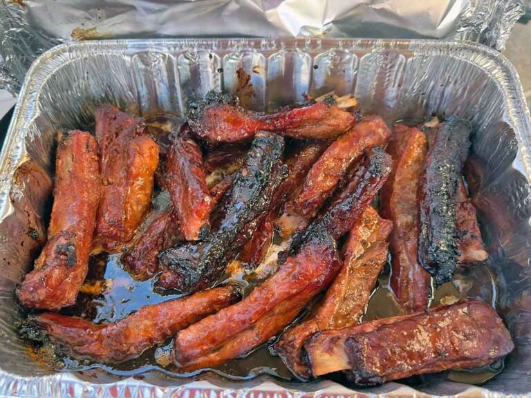 Ribs reheating in a foil-covered pan with drippings to keep the meat moist.