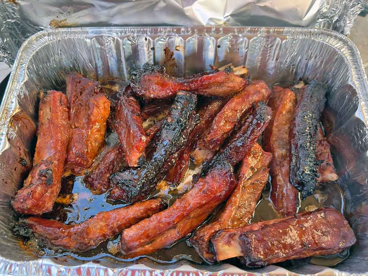 Ribs reheating in a foil-covered pan with drippings to keep the meat moist.
