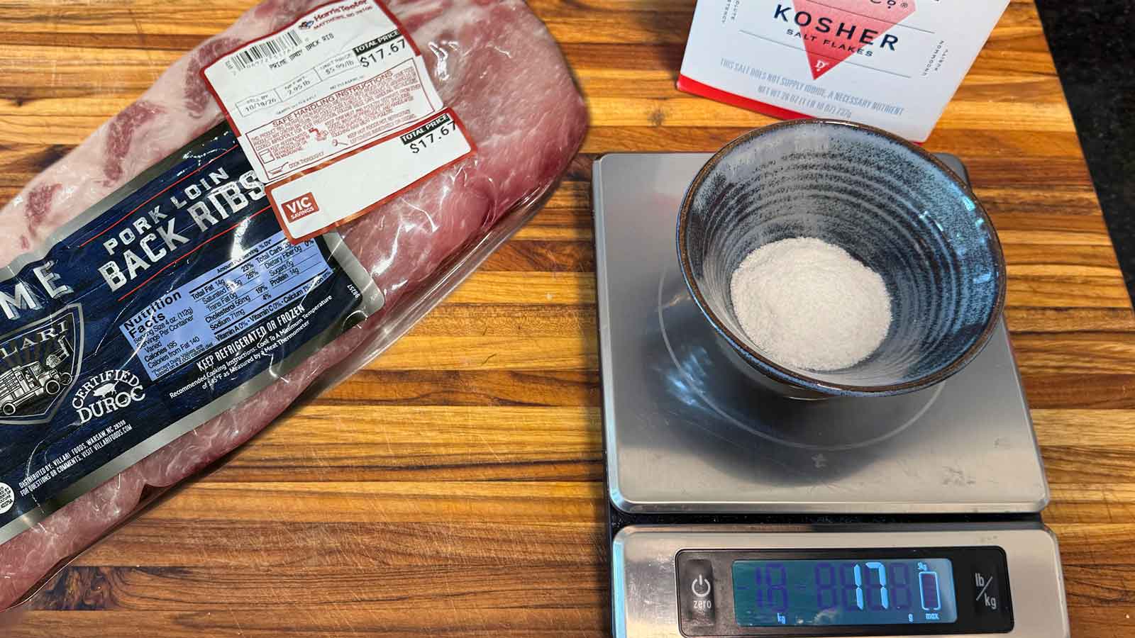Kosher salt weighed on a digital scale beside ribs for a dry brine by weight.