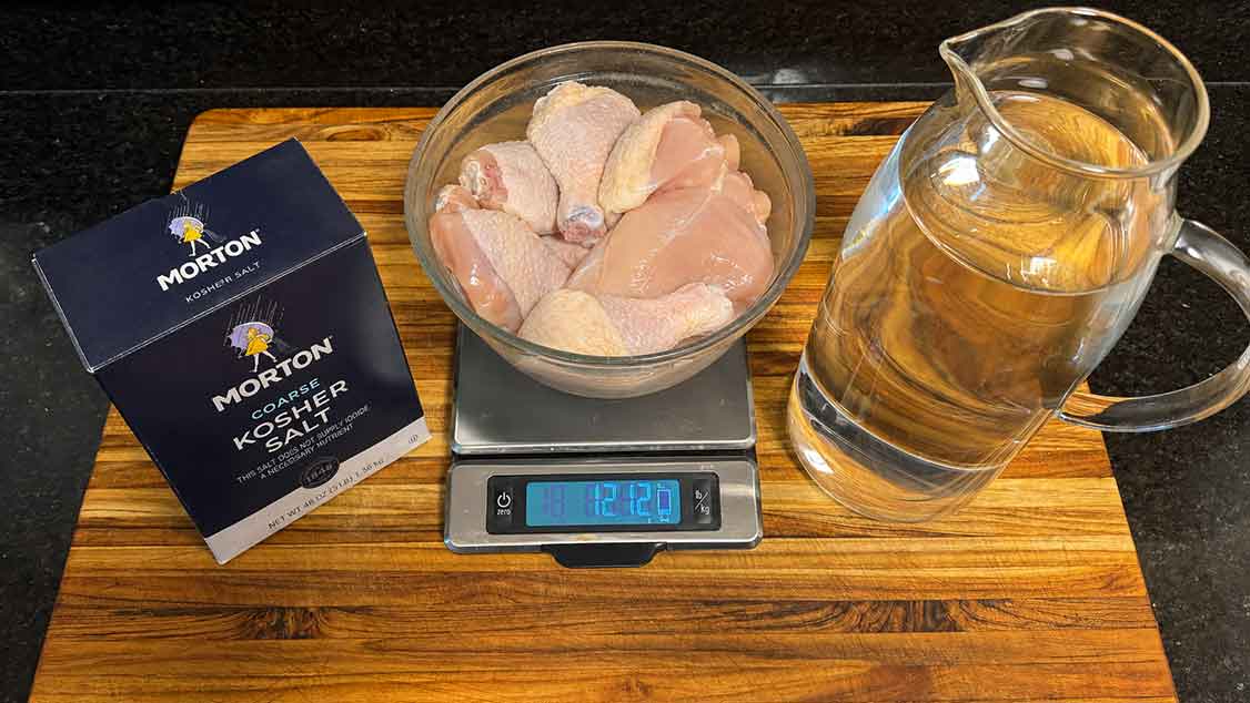 Chicken pieces on a scale beside kosher salt and water for a wet equilibrium brine.