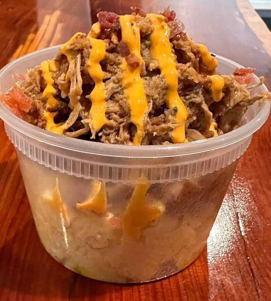Mac and cheese bowl topped with pulled pork and Sriracha mayo.