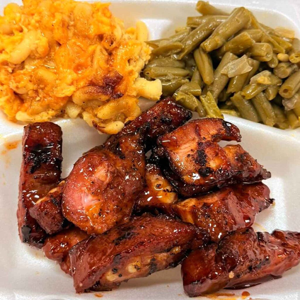 Sauced rib tips on plate with Mac and cheese and green beans.