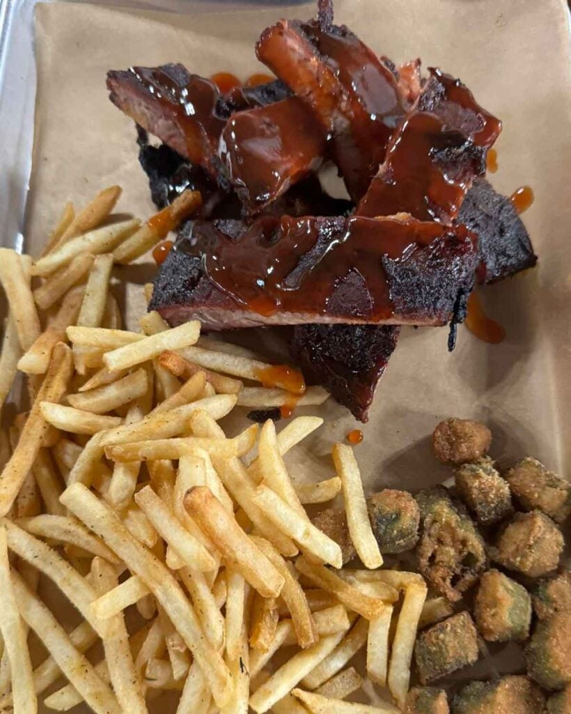 Stacked ribs on tray with fried okra and French fries.