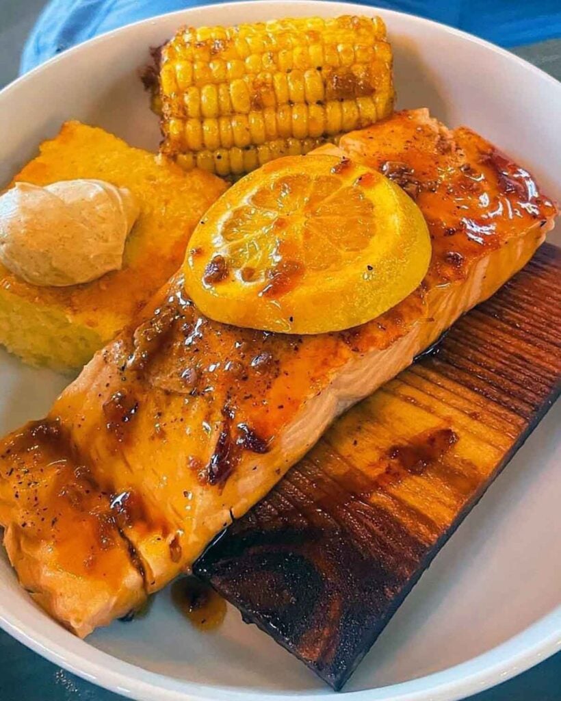 Smoked salmon on cedar plank with lemon and sides.