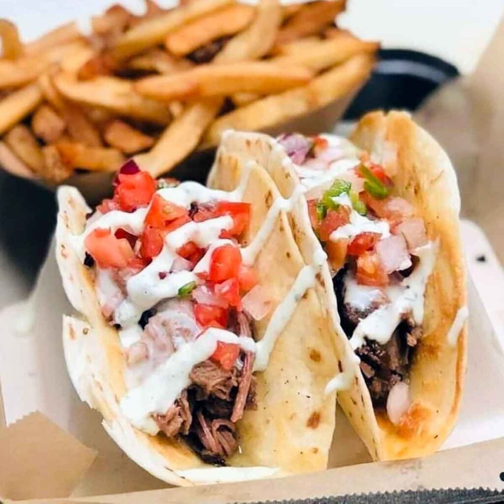 Two tacos with fries.